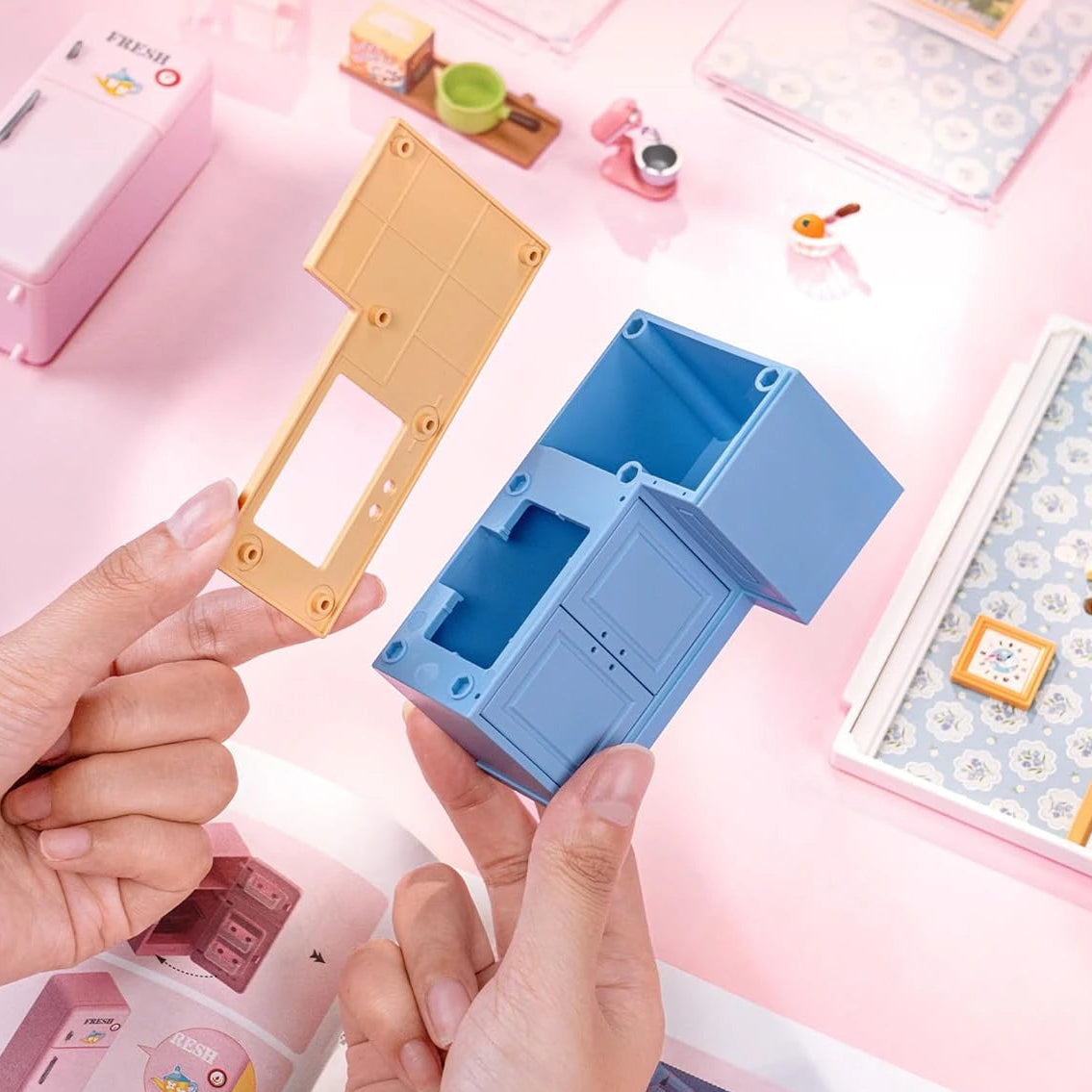 Unboxing scene with a blue box and pink background featuring stationery items.
